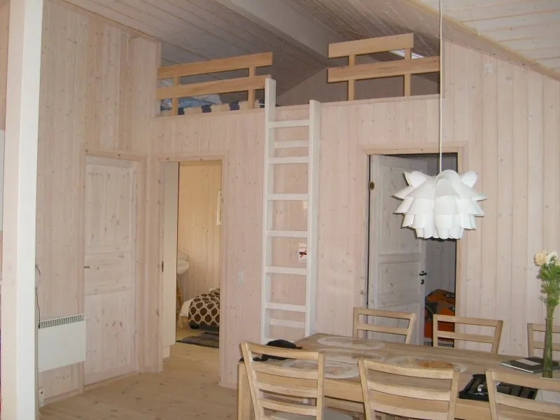 Interiör i ljust trä med loft och stege