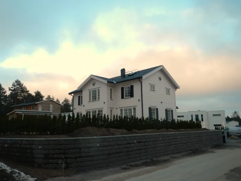 Vit villa i skymningsljus bakom en stödmur